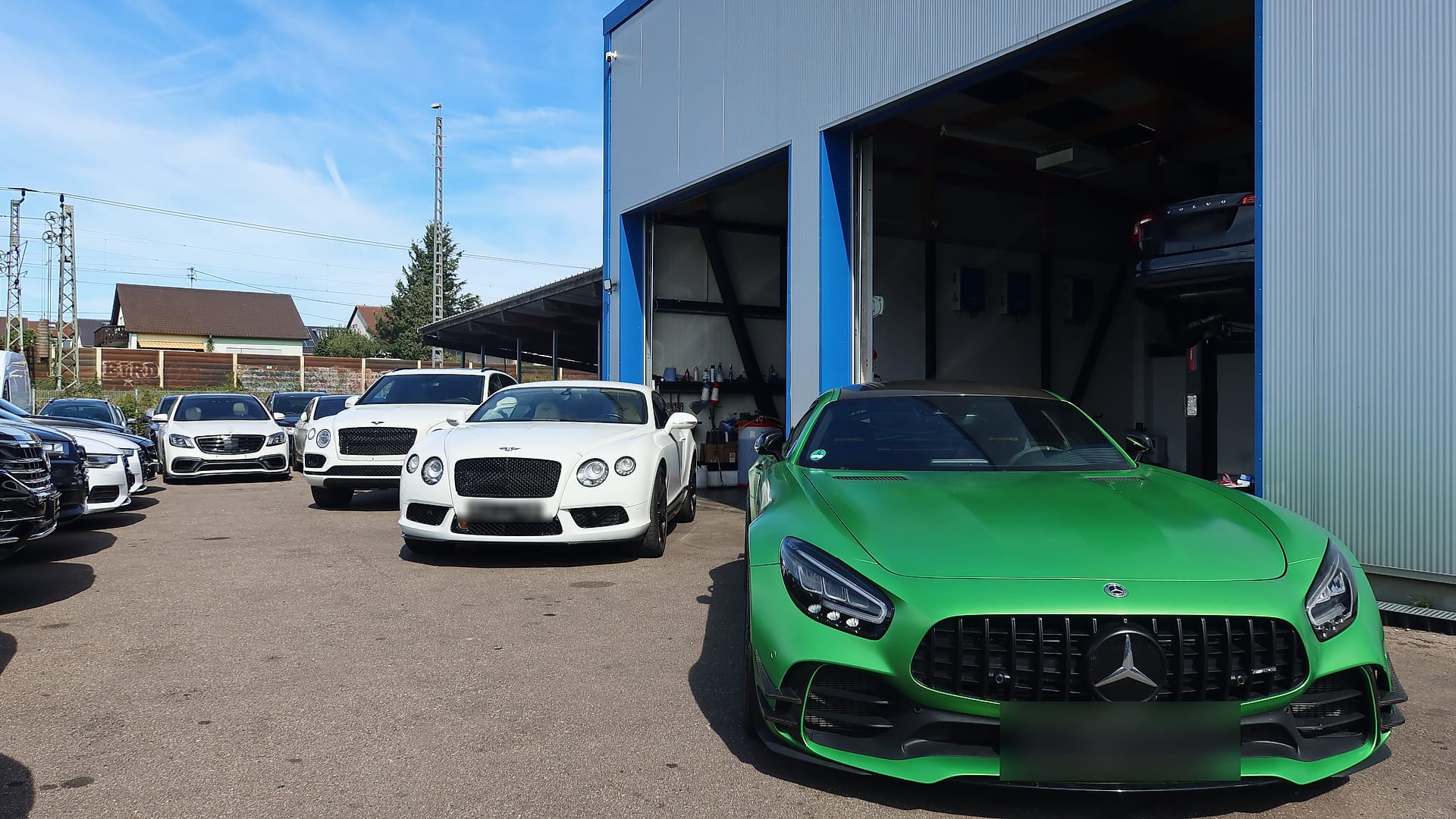 Ein grüner Mercedes-AMG GT R und zwei Bentley vor der Halle des Autohauses