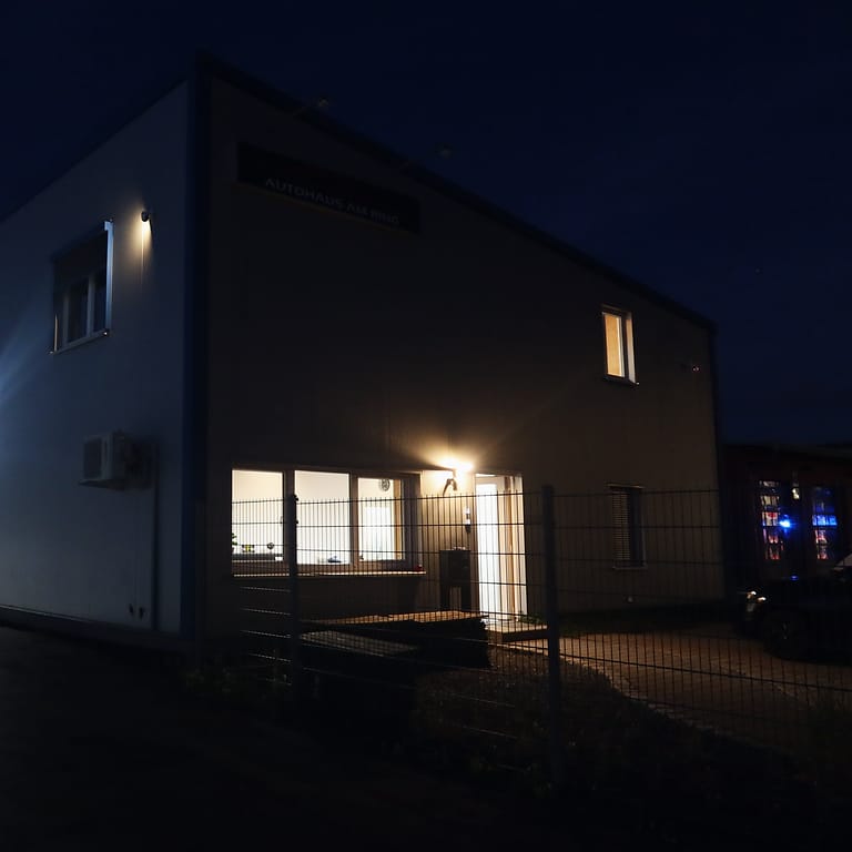 Die Halle des Autohauses am Abend, Licht in den Fenstern und an der Tür