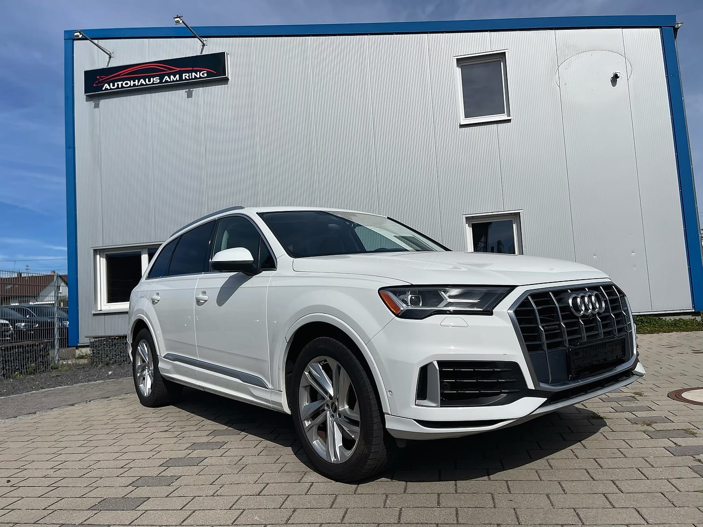 Audi Q7 55 TFSI in Weiß, schräg von vorn, vor der Halle in Illingen