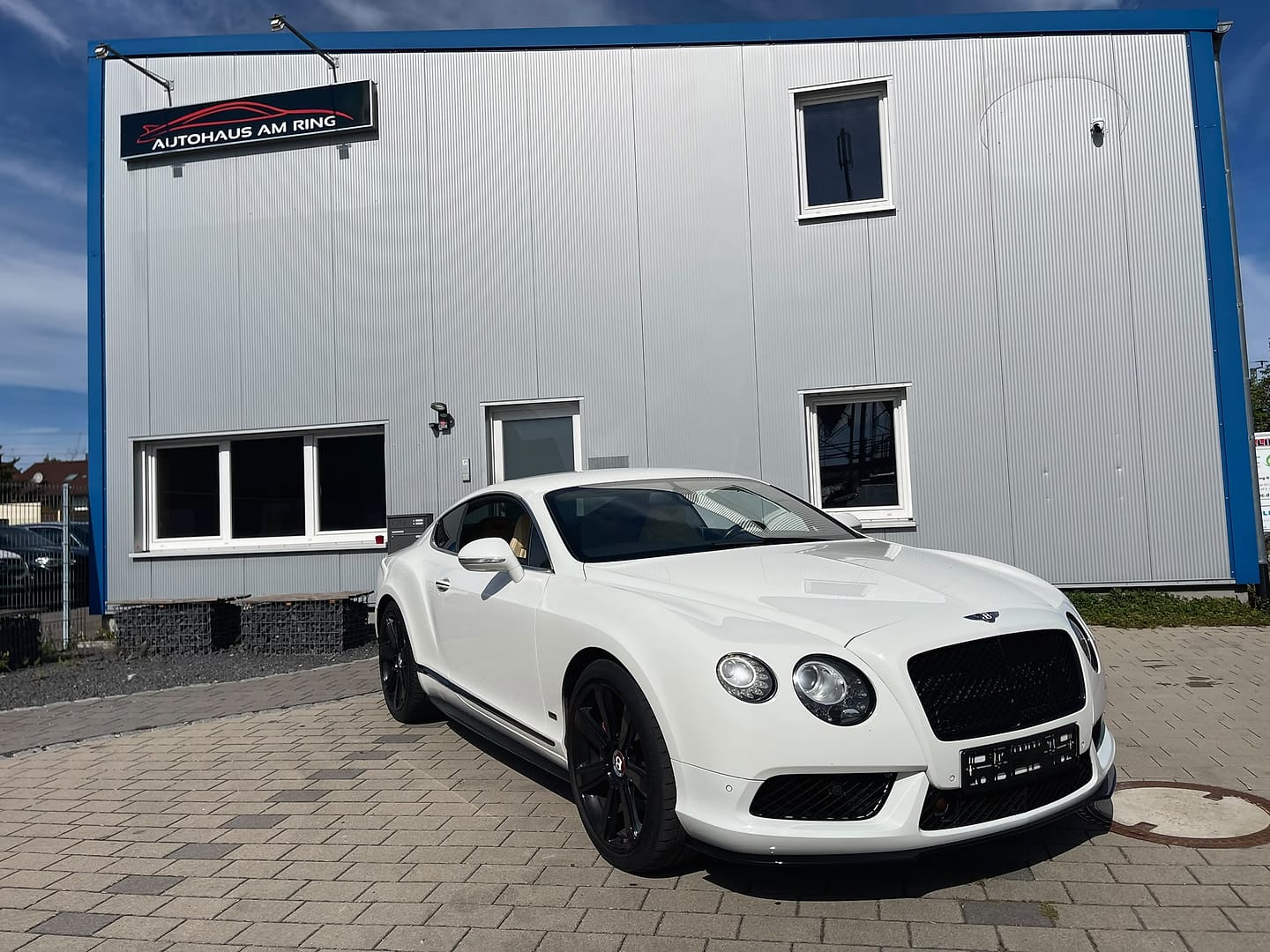 Bentley Continental GT V8 S in Weiß, schräg von vorn, vor der Halle in Illingen