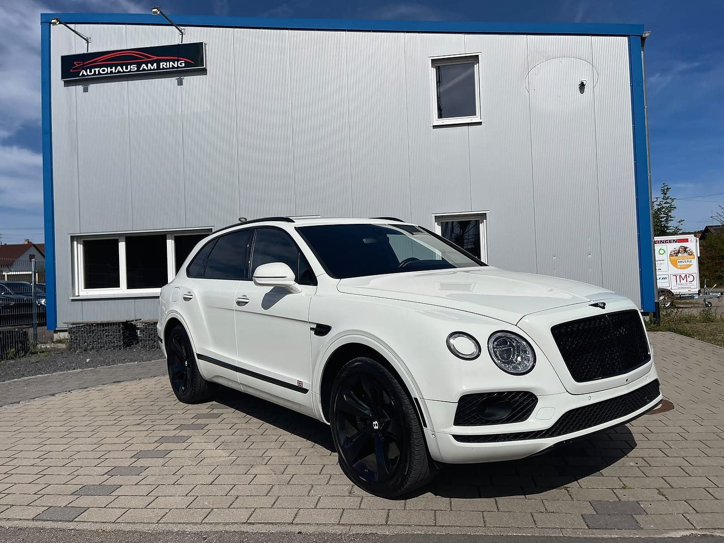 Bentley Bentayga W12 in Weiß, schräg von vorn, vor der Halle in Illingen