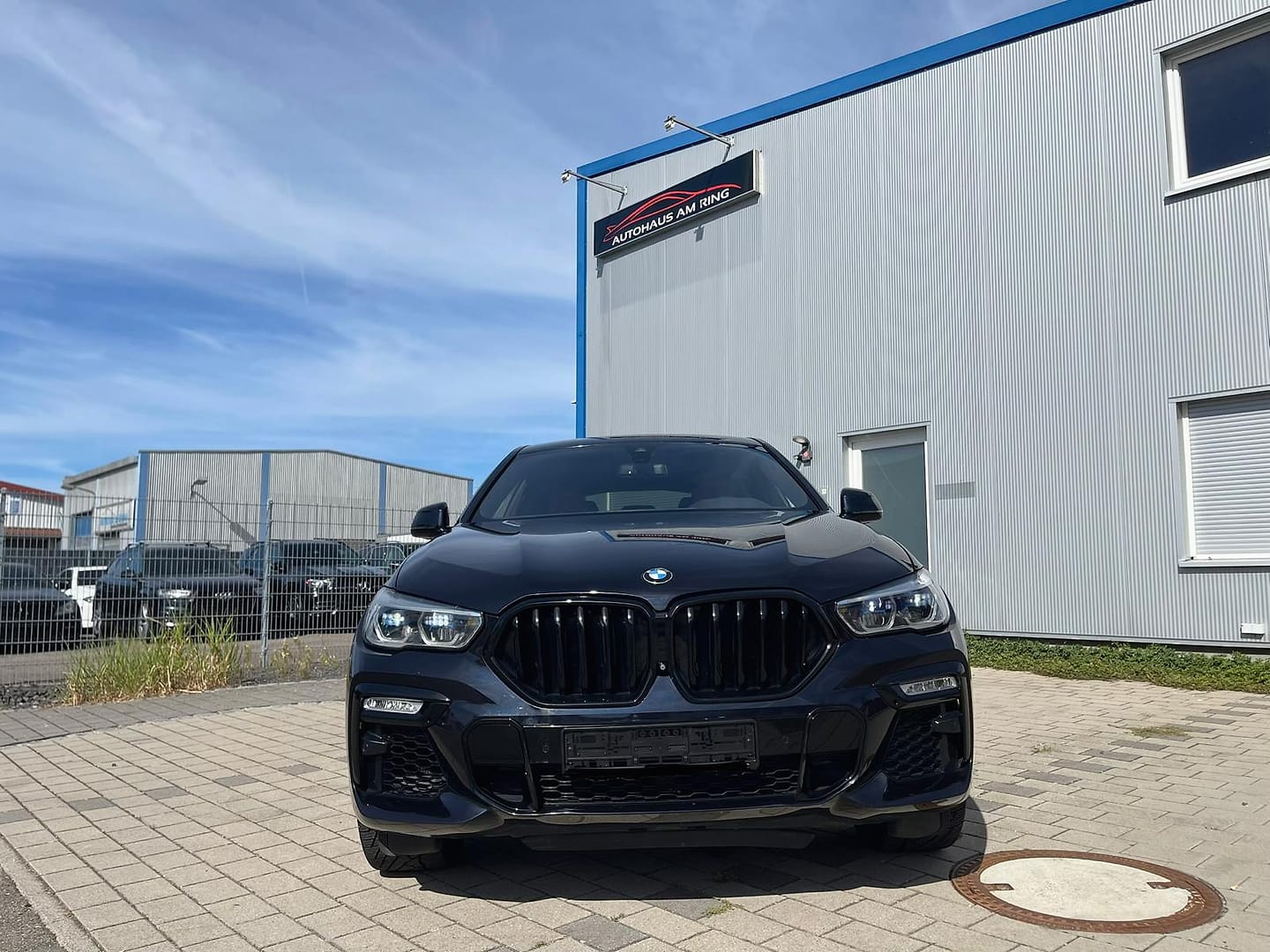 BMW X6 in Schwarz, schräg von vorn, vor der Halle in Illingen
