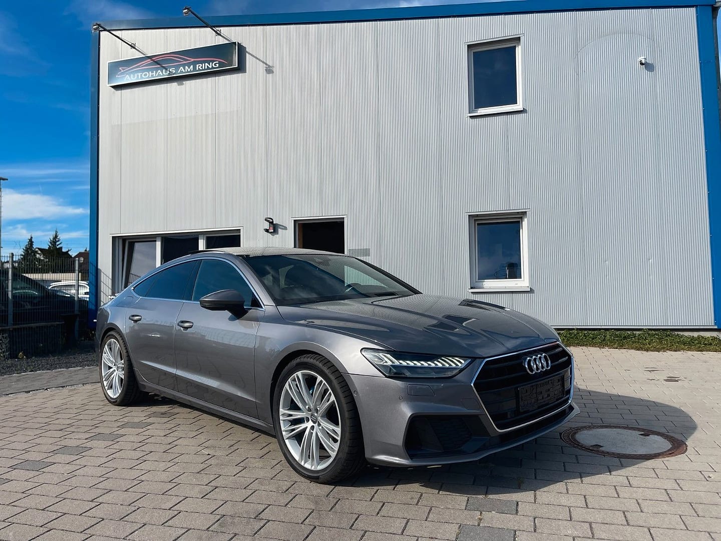 Audi A7 Sportback 45 TDI quattro, schräg von vorn, vor der Halle in Illingen