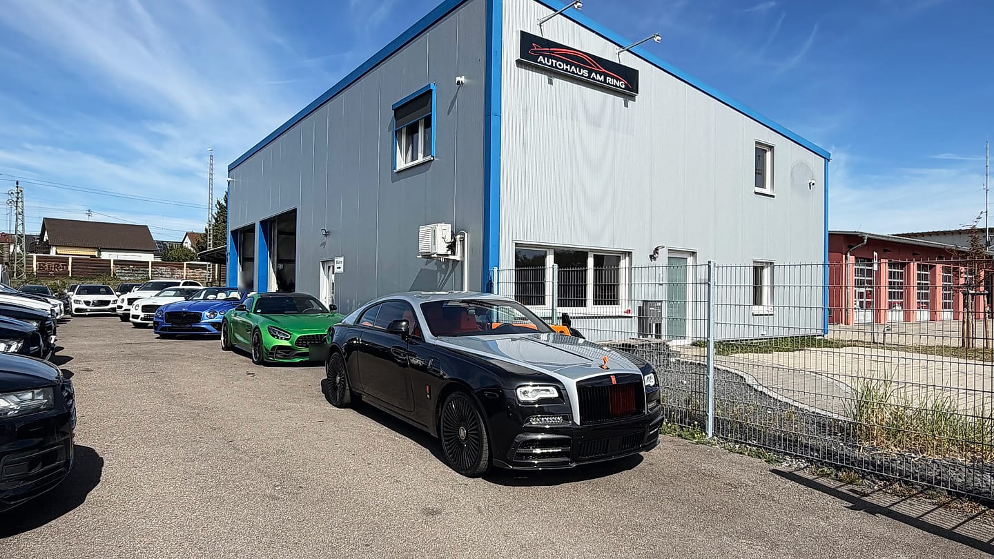 Die Halle des Autohauses am Ring in Illingen mit dem Schild an der Fassade, davor ein schwarz-silberner Rolls-Royce Wraith und die Fahrzeugreihen