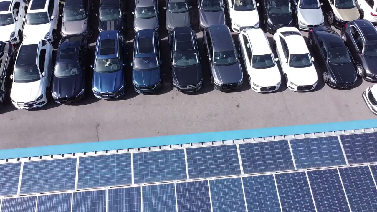 Luftbild: das Dach der Werkstatthalle mit Photovoltaik, daneben die Fahrzeugreihen auf dem Hof